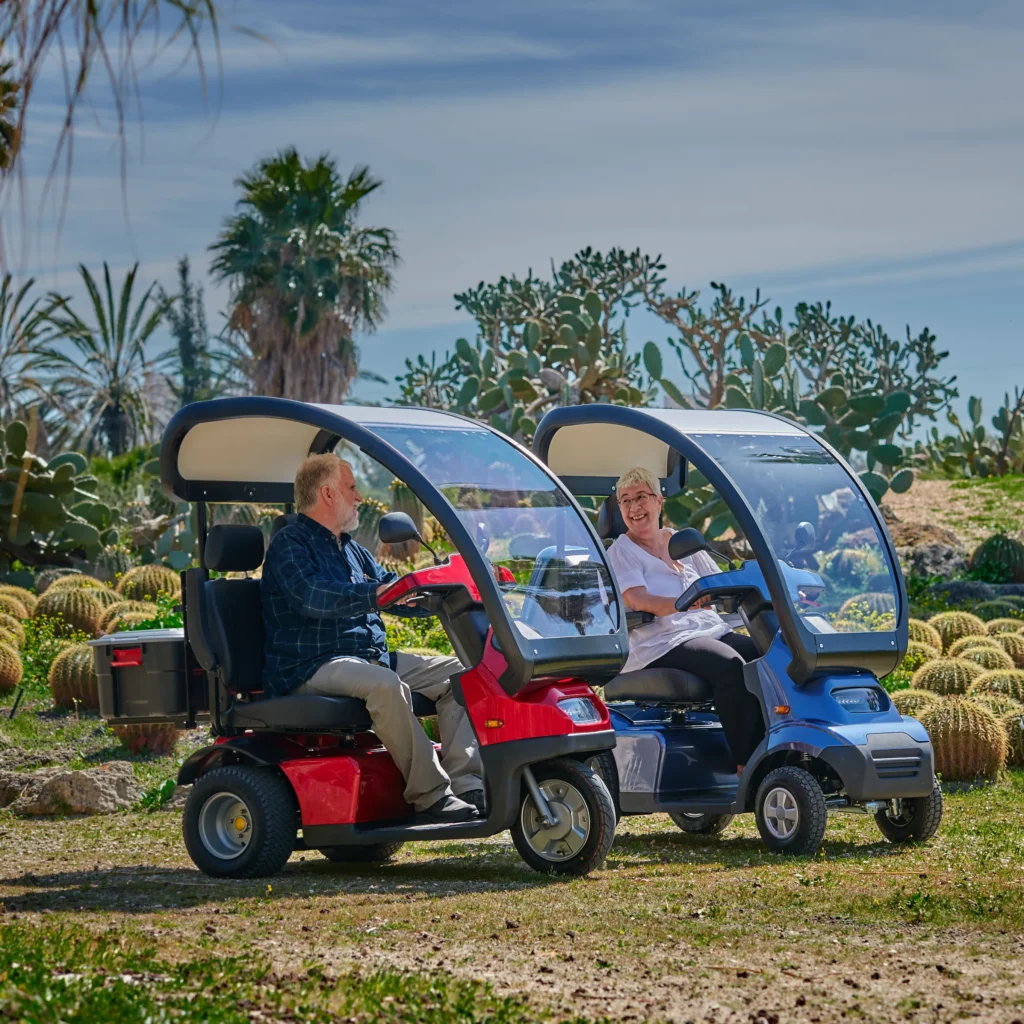 Lifestyle Image Side View of Red Afiscooter S3 Mobility Scooter with Canopy Golf Tires, Blue Afiscooter S4 with Canopy Mobility Scooter