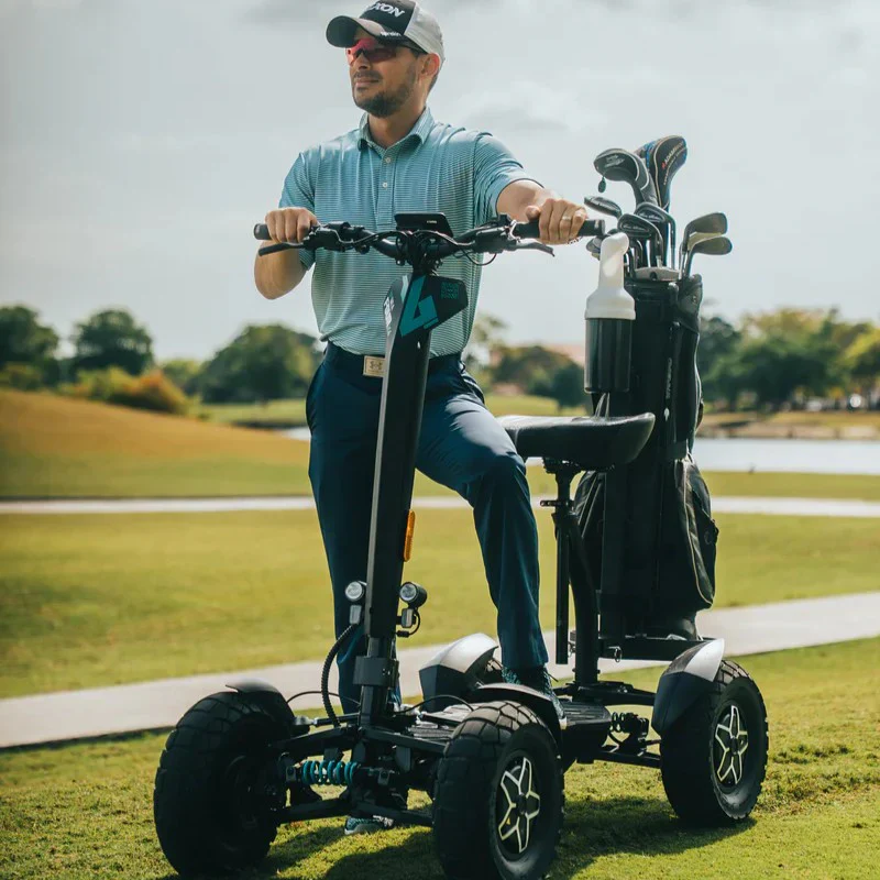 Front view of a person standing on the MIA Four X2 scooter with a golf bag attached on a golf course